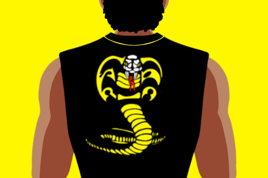 A man wearing a black top with a Cobra Kai logo on it, yellow background.