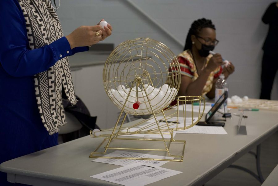 A bingo cage filled with numbered ping-pong balls sits on a table, as former Ald. Robin Rue Simmons (5th) holds one in her hand.