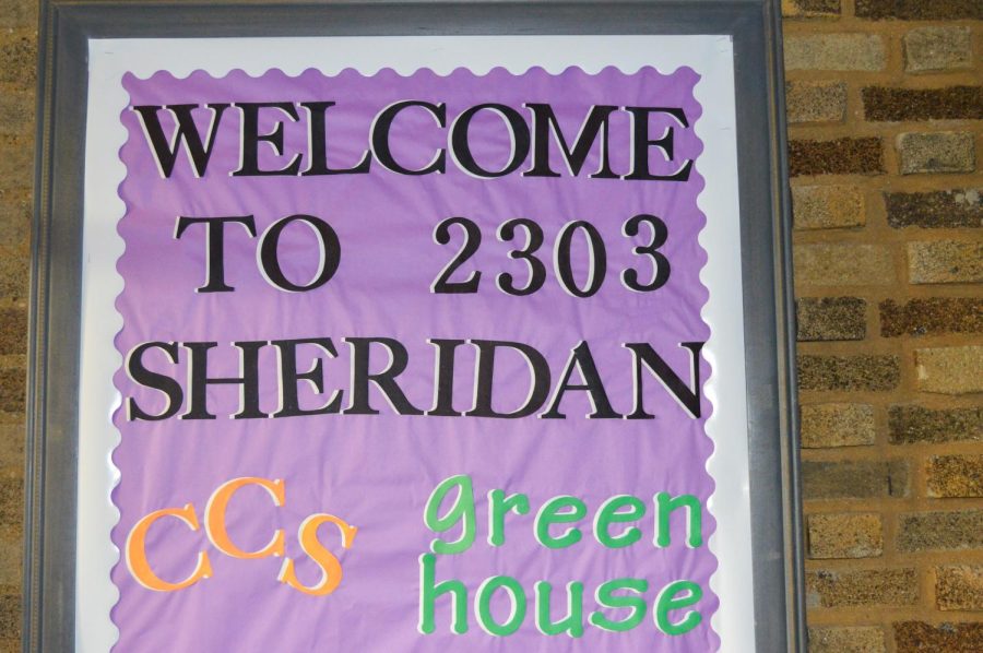 Purple sign at NU’s Green House, sign reads “Welcome to 2303 Sheridan” with Green House spelled out in green on the lower right.