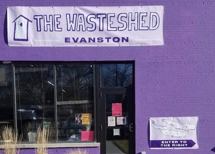 The exterior of a storefront. The wall is brick painted purple. A large banner above the door reads, “The WasteShed Evanston,” also in purple. There is a purple sign with whales on it that reads, “Enter to the right.”
