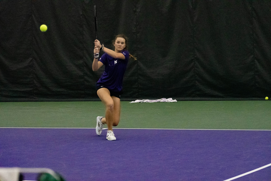 Tennis player in purple hits the ball