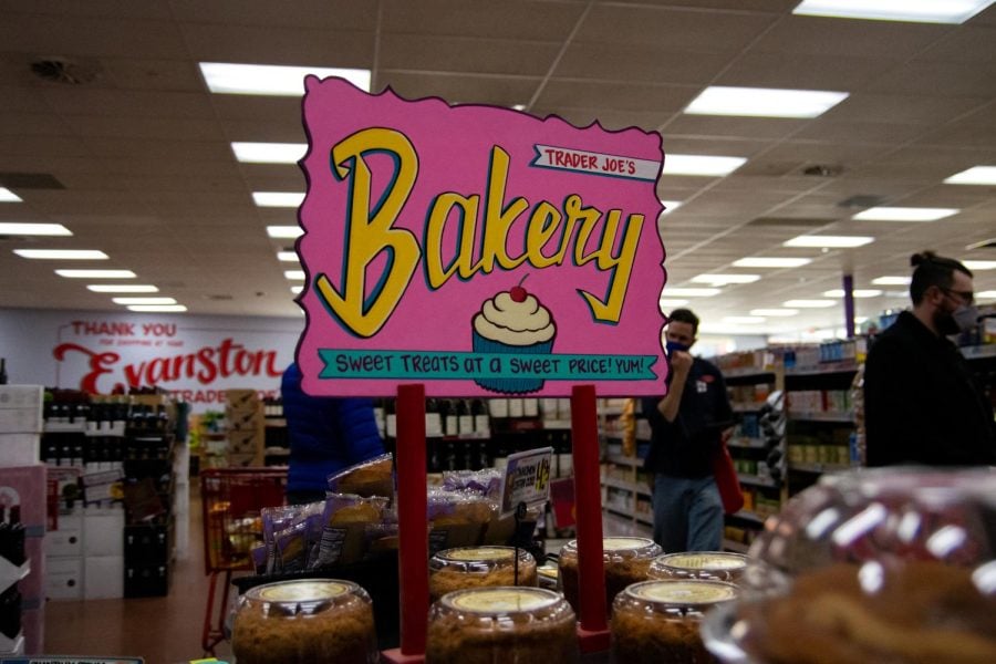 Pink and yellow bakery sign at Evanston Trader Joes. Cakes sit below on a table.