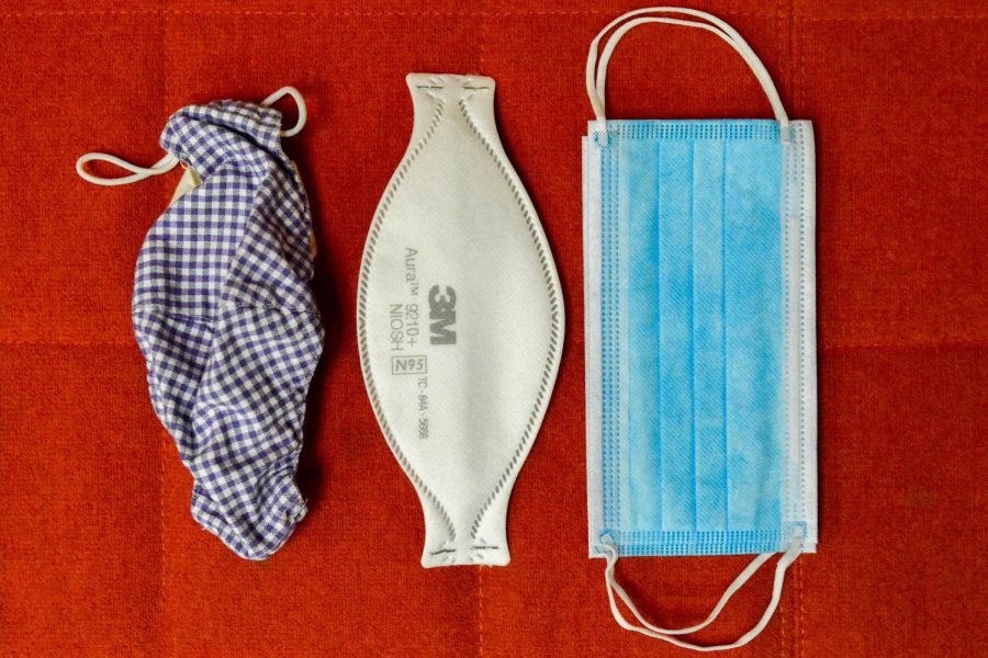 A cloth mask, a surgical mask and an N95 mask side by side.