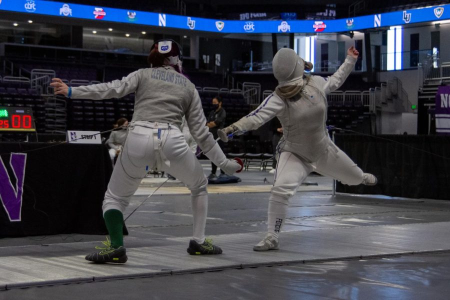 The fencer on the left jumps as they reach their weapon towards their opponent located on the left.