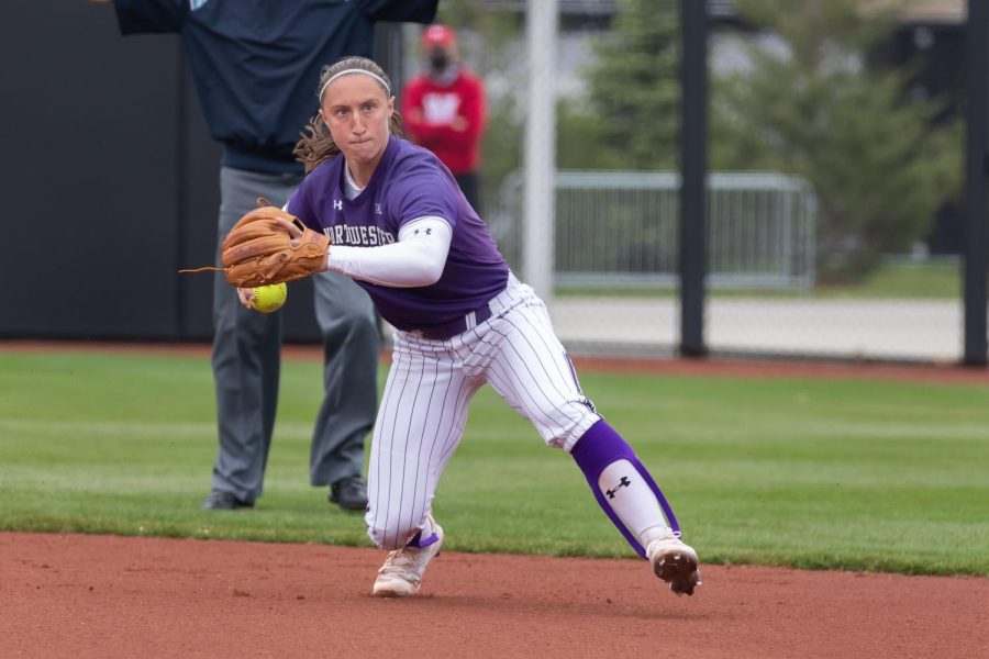 Softball+player+in+purple+and+white+uniform+standing+on+infield+prepares+to+throw+the+ball.