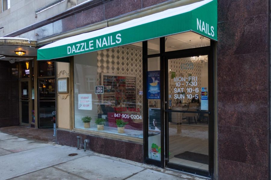 The exterior of Dazzle Nails with a green awning. In the windows there is a “10% student discount” sign.