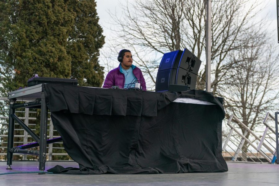 A man in a purple puffer DJs on stage.