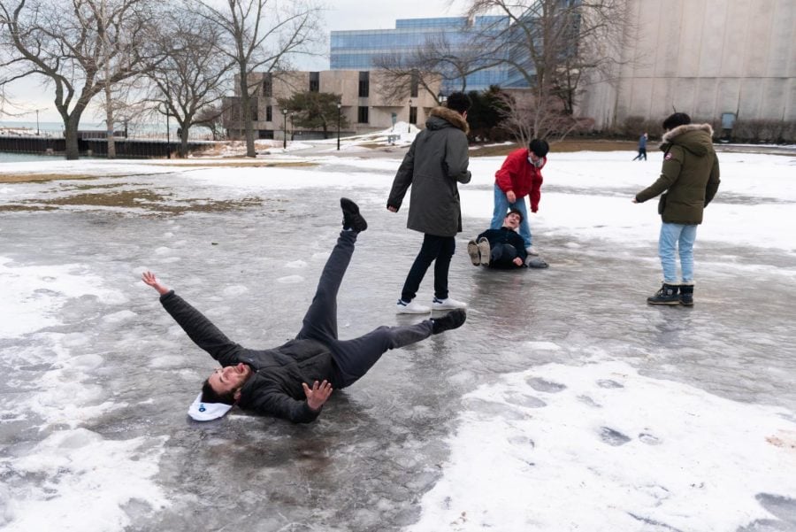 A person slips and falls on the ice while another person is seen lying on the ice in the background.