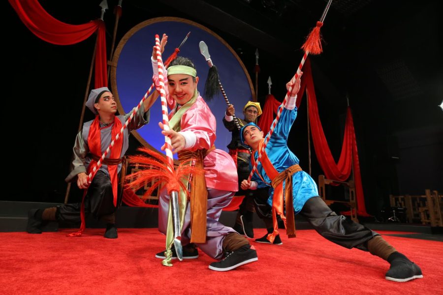 Four cast members from The Ballad of Mu Lan pose on the stage. Each is wearing robes the colors blue, pink, black and gray.