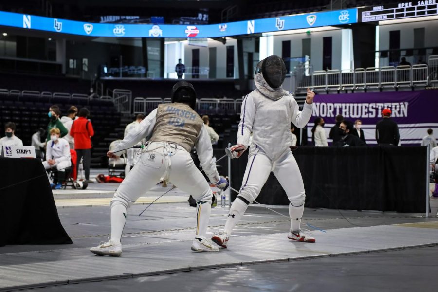 The fencer on the right pumps their fist after a match with the opponent leaning forward on the left.