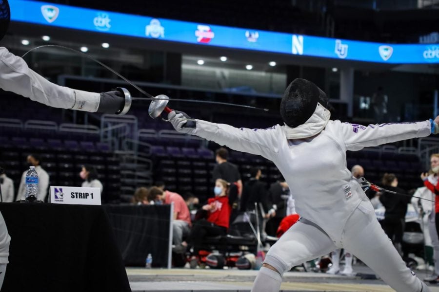 Fencers+in+white+uniforms+lunge+at+each+other.+One+makes+contact%2C+and+their+weapon+extends+outwards.