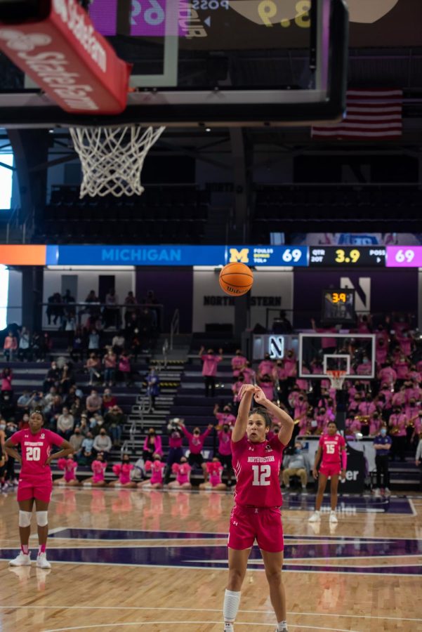 Girl in pink uniform takes a shot with a basketball