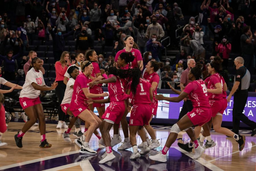 A group of people in pink jerseys jump and cheer.
