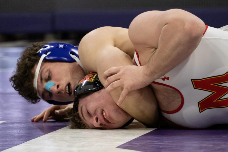 A wrestler pins down another wrestler with their arm around their neck.
