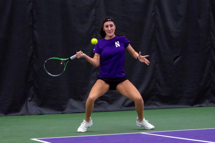 A tennis player is about to hit a ball with her tennis racket.