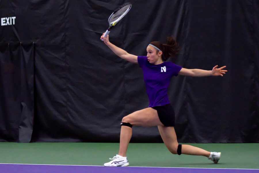 A tennis player extends her arms after hitting a tennis ball.