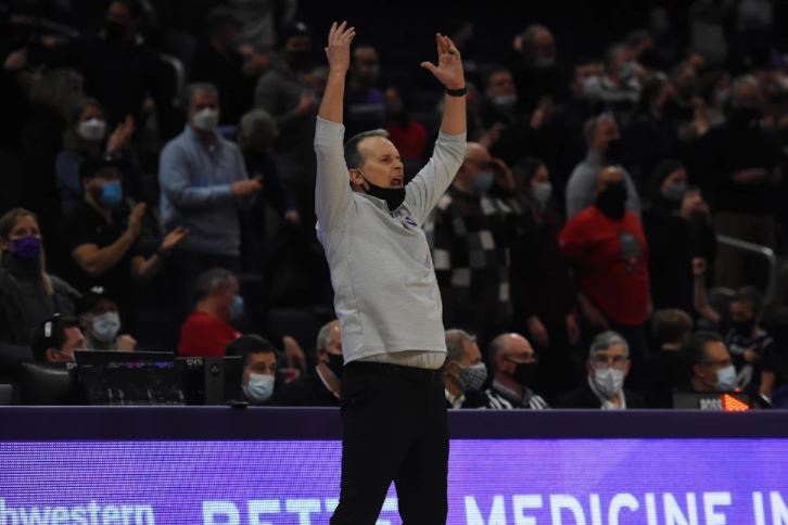 A basketball coach throws his arms in the air.