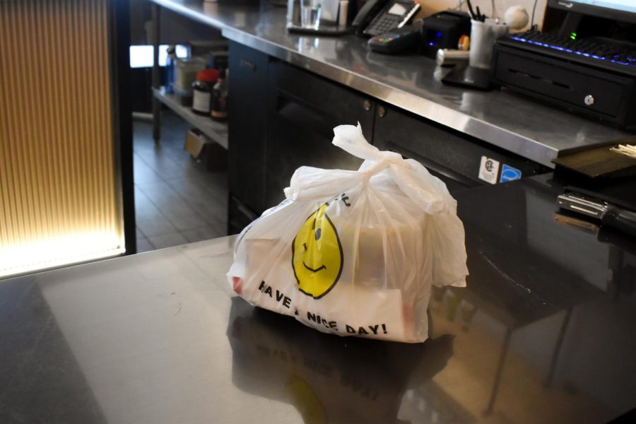 A white plastic bag with a yellow smiley face that says “HAVE A NICE DAY!” on a dark countertop.