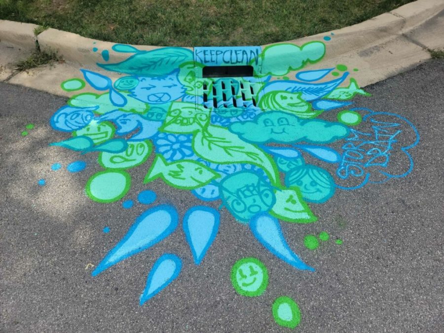 Storm drain art with green and blue colors and vibrant designs