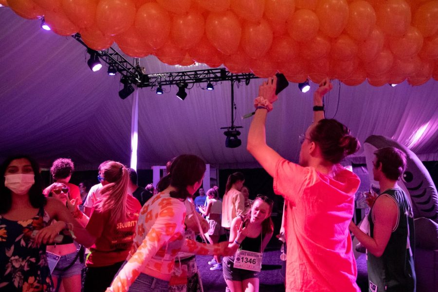 Students dance under orange balloons. 