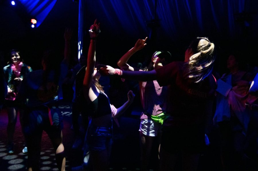 Several students dance together in a tent.