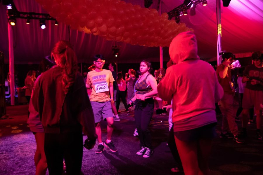 Students dance in a circle in a tent.