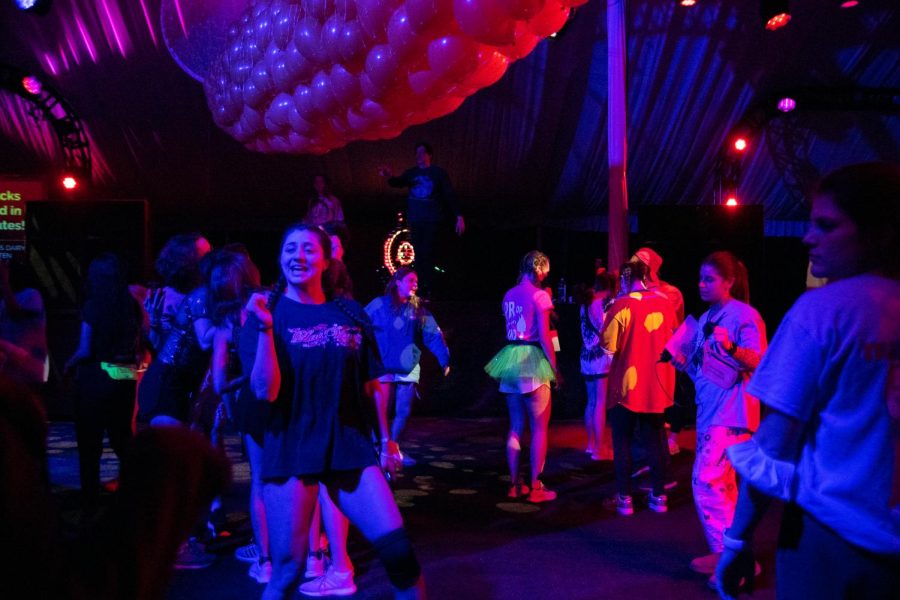 Students dance in a tent with balloons suspended in a bag from the ceiling.