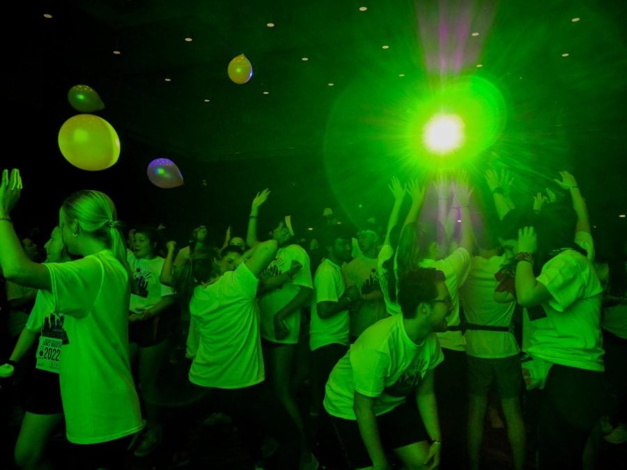 A crowd of students dancing in a room with green lighting.