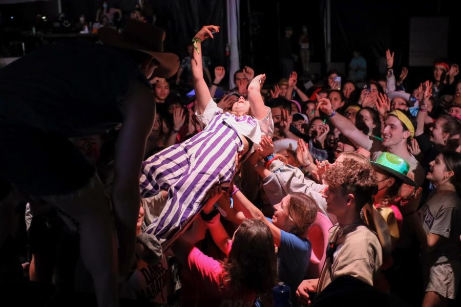 A girl in striped overalls crowdsurfs.