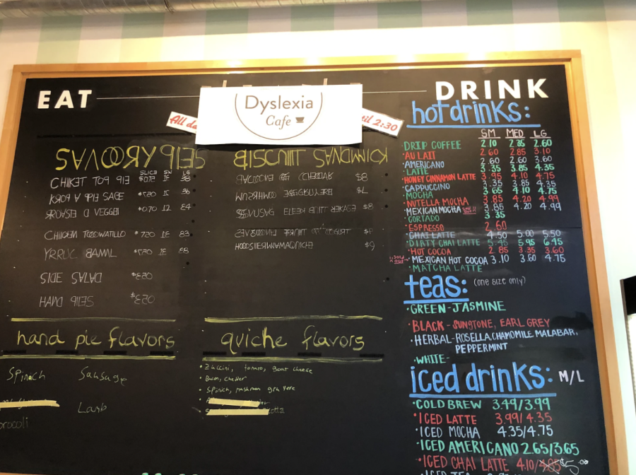 A menu written on a blackboard, with a sign reading ‘Dyslexia Cafe’ taped at the top. Many of the words are jumbled, with letters appearing backward or upside down and in different orders.