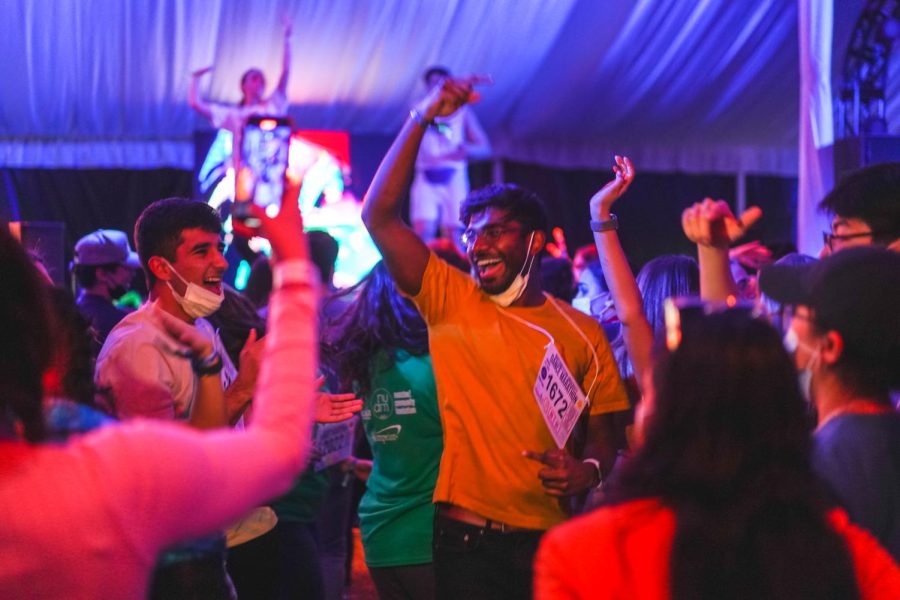 A crowd of students dance in a tent with lights and music