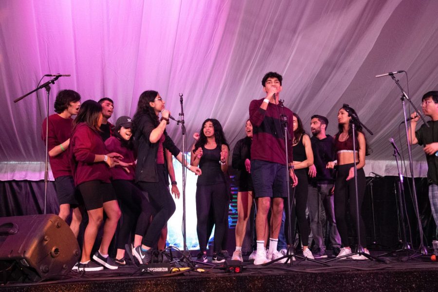 The student a cappella group Brown Sugar performs on stage, wearing burgundy shirts and black bottoms.
