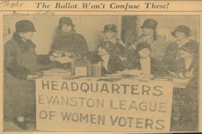 Women sit at a table with a sign reading ‘Headquarters Evanston League of Women Voters.’