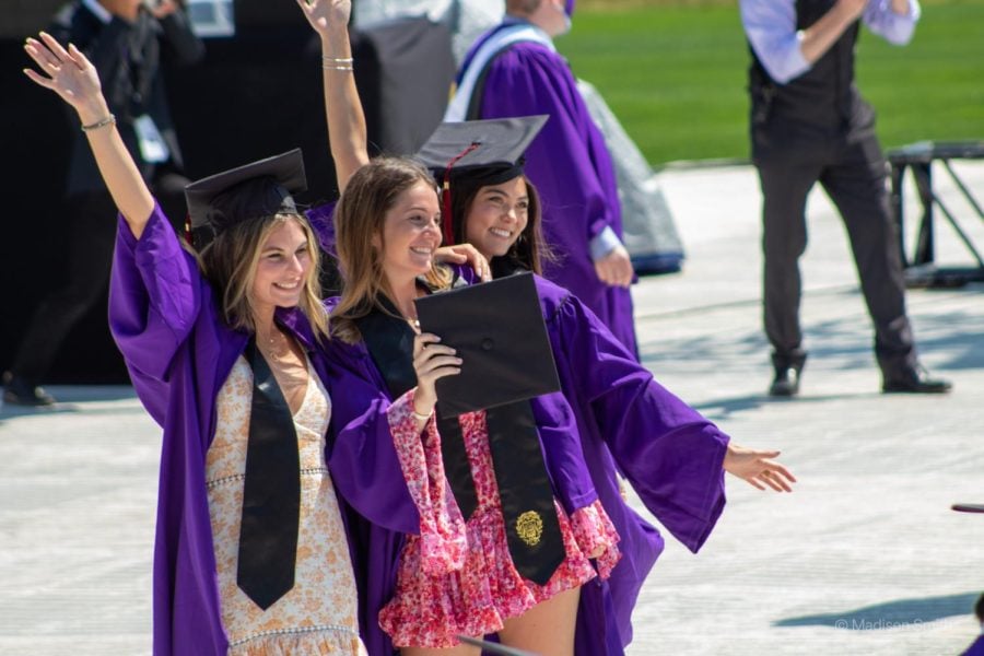 Three Northwestern graduates pose for the camera in purple caps and gowns.