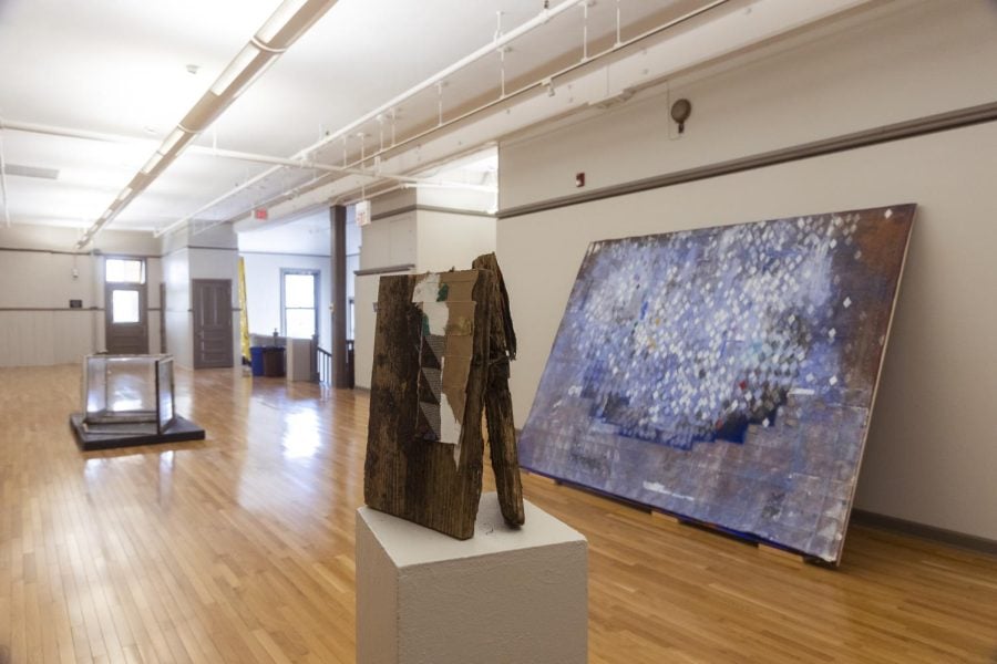 A+brown+mixed-media+sculpture+sits+on+a+pedestal+in+a+gallery.
