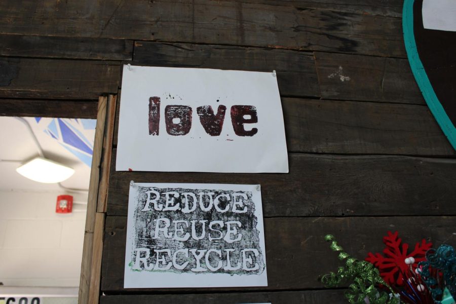 Two white paper signs with one reading “Love” on the top and the other reading “Reduce, Reuse, Recycle” on the bottom.