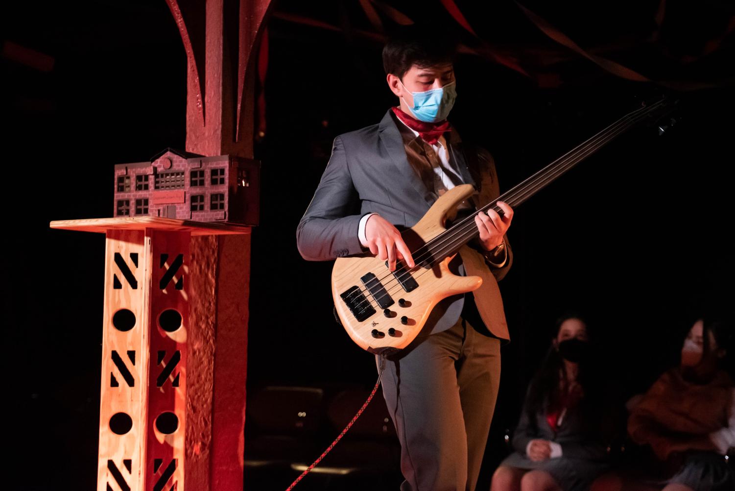 An+actor+in+a+suit+plays+an+electric+bass.