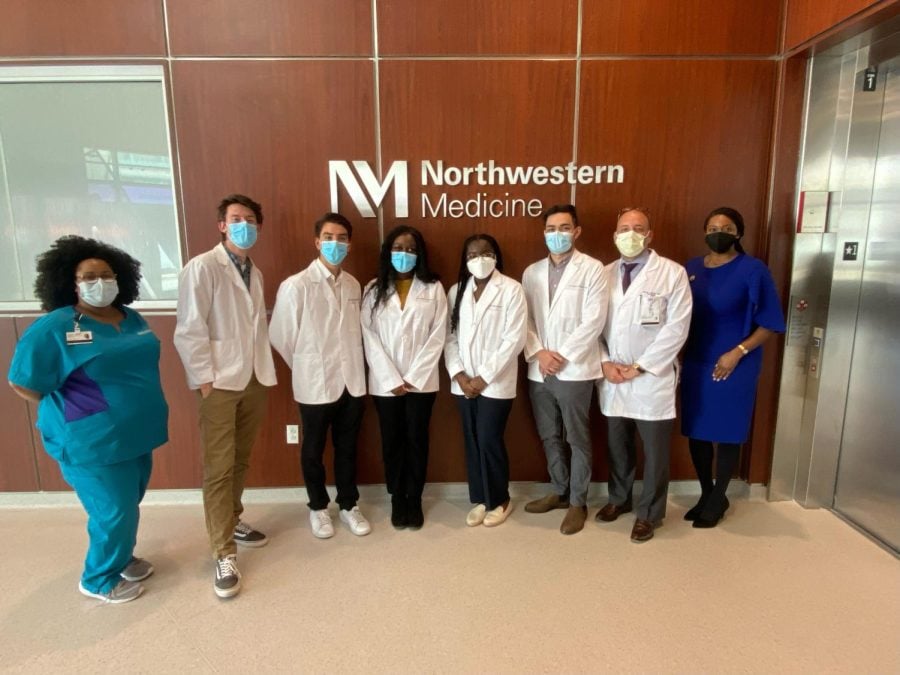 Picture of five pre-med students in their lab coats alongside three health professionals.