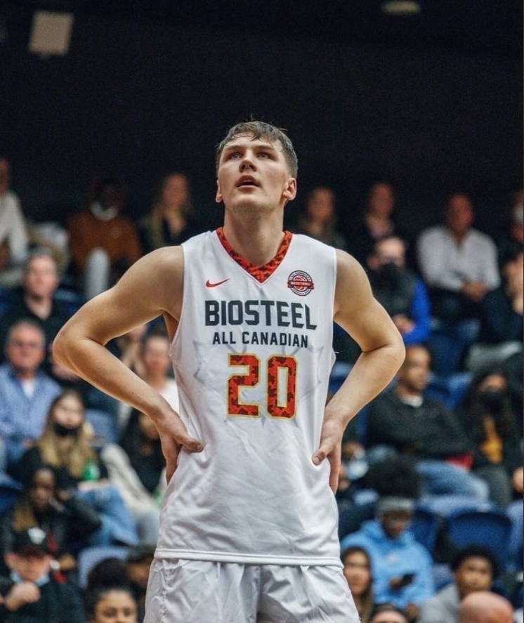 A basketball player in a white jersey stands on the court.