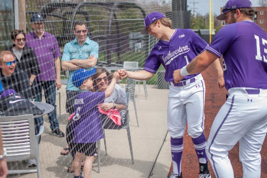 A player wearing a purple jersey gives a toddler fan wearing a purple jersey a fist bump.