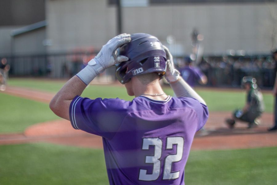  A player in a purple jersey fixes their helmet in preparation to bat.