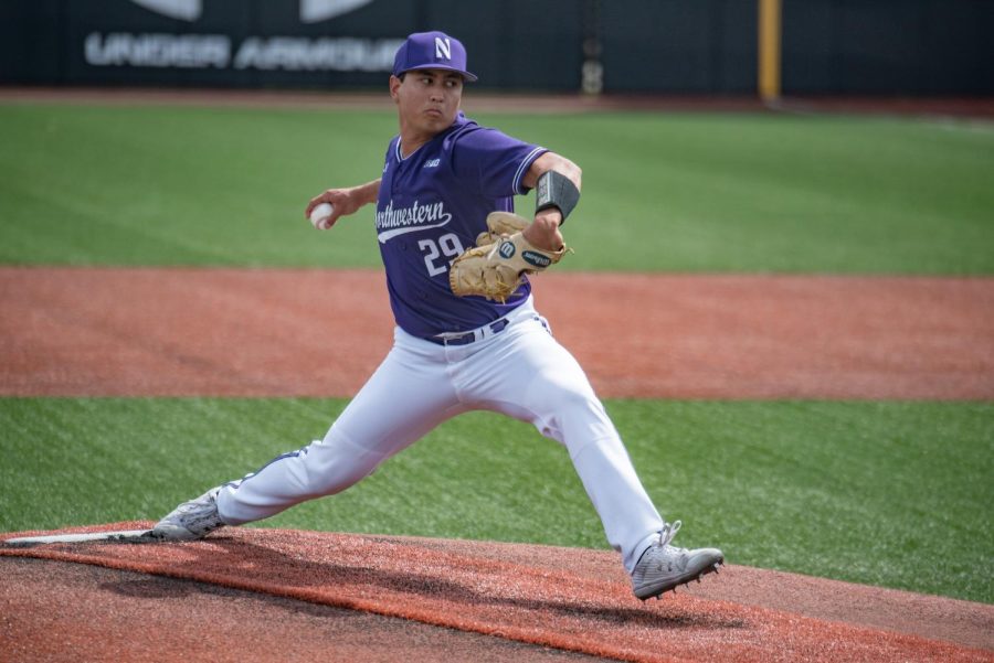 A player wearing a purple jersey that reads “Northwestern 29” takes a large step and throws a baseball.