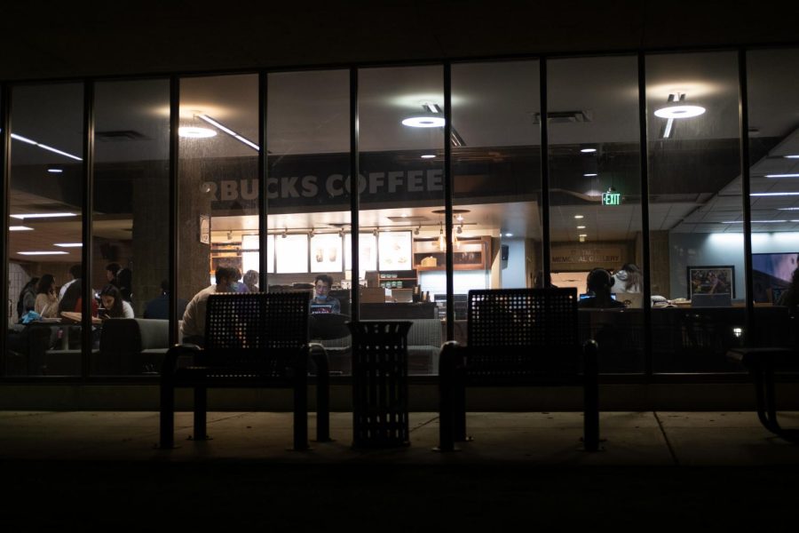 Starbucks in Norris University Center lit up at night with students studying in front.
