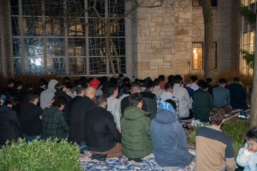 A group of people sit kneel in prayer outside.