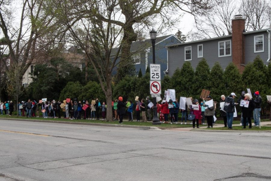A crowd of people stand along Ridge Avenue during the annual YWCA Stand Against Racism holding signs.