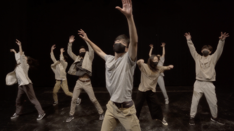 Gene Kim stands center surrounded by members of his cast with arms raised.