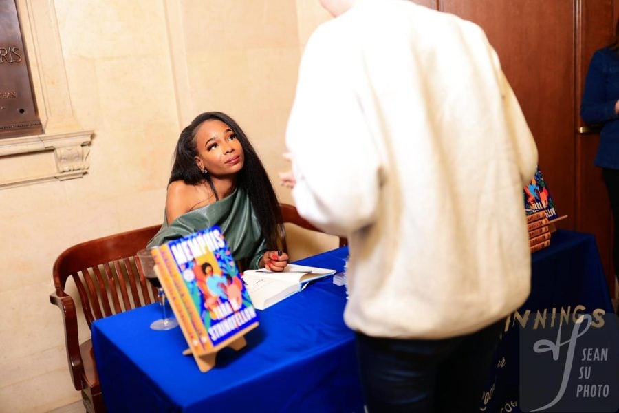 Tara Stringfellow sits at a blue table signing copies of “Memphis” following the reading.