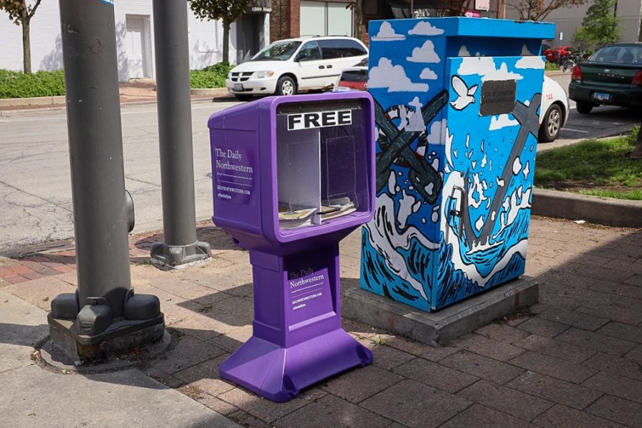 purple newsstand next to a blue structure with an anchor painted on.