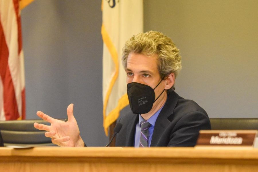A close-up photo of Daniel Biss sitting at a desk with a Black N95 mask on.