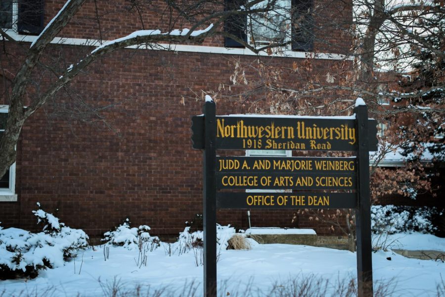 Snow falls on a sign that reads “Judd A. Marjorie Weinberg College of Arts and Sciences Office of the Dean.”